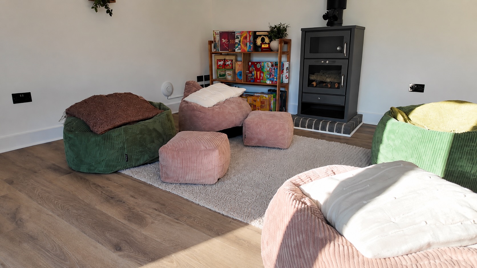 Cozy shared lounge with corduroy bean bags, a rug, log burner and a games shelf