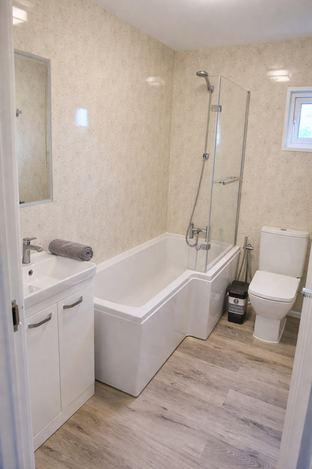Bright bathroom with a bath, shower screen and fresh towels