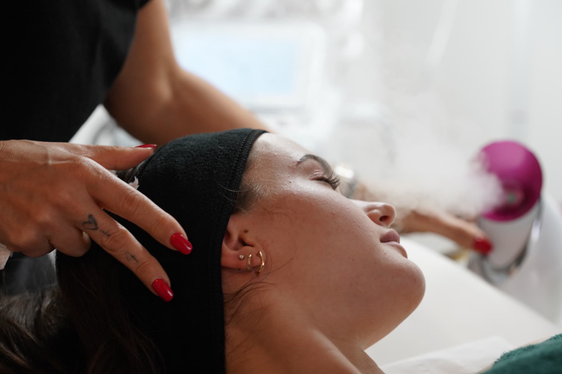 Therapist giving a guest a facial treatment in the bright treatment room