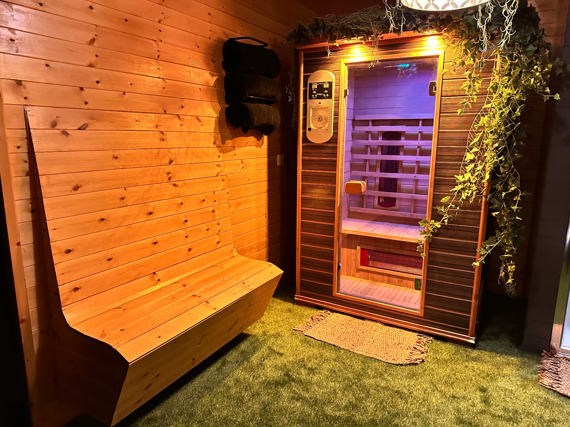Infrared sauna cabin in a cedar-lined room with a bench and trailing ivy